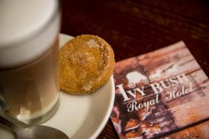 a cup of coffee sitting next to a doughnut at Ivy Bush Royal Hotel by Compass Hospitality in Carmarthen