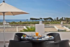 a table with drinks and an umbrella on a balcony at Sao Rafael Holidays in Albufeira