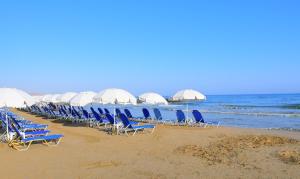 a row of chairs and umbrellas on a beach at Magda Hotel Club in Gouves