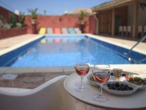 RoquebrunにあるModern villa with private pool in Roquebrunの- プールサイドのテーブルの上でのワイン2杯とフルーツボウル