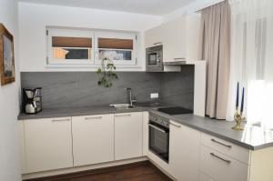 a white kitchen with white cabinets and a sink at Bergruh Steeg in Steeg