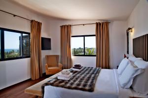a hotel room with a bed and a chair and windows at Sao Rafael Holidays in Albufeira