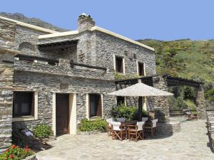 a stone building with a table and an umbrella at Anastasia Luxury Villas in Gavrio
