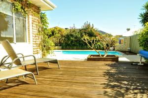 a wooden deck with chairs and a swimming pool at Halls Head Holiday Home in Mandurah