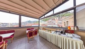 un restaurante con mesa, sillas y ventanas grandes en Old Meidan Tbilisi By Urban Hotels, en Tiflis