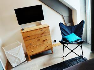 a bedroom with a tv and a chair and a dresser at Maison de Louna in La Bourboule