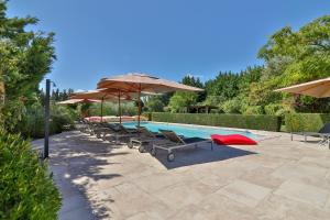 a swimming pool with lounge chairs and umbrellas at Les Carmes and spa in Le Thor