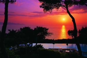 a sunset over a body of water with trees at Boutique Hotel Torre Di Cala Piccola in Porto Santo Stefano