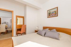 a white bedroom with a bed and a table at Villas Kampor in Kampor