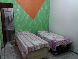 a small room with two beds and a bathroom at Pousada Santa Helena in Juazeiro do Norte