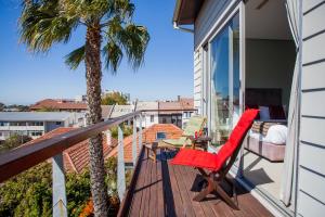 a balcony with a red chair and a table and a palm tree at The One 8 Hotel in Cape Town