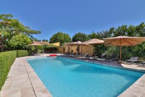 a swimming pool with chairs and umbrellas at Les Carmes and spa in Le Thor