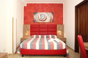 - un lit rouge dans une chambre ornée d'une peinture murale dans l'établissement Coralia Bed & Breakfast, à San Vito Lo Capo