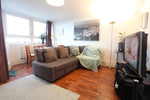 uma sala de estar com um sofá e uma televisão em Chelsea off Kings Road One Bedroom Apartment with balcony em Londres