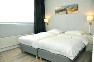 1 dormitorio con 1 cama grande con sábanas blancas en Residence Le Mistral en Noordwijk aan Zee