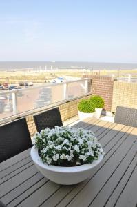 a table with a bowl of flowers on a balcony with the beach at Residence Le Mistral in Noordwijk aan Zee