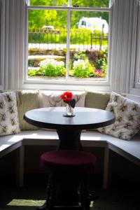 une table avec un vase de fleurs devant une fenêtre dans l'établissement The Elks Head Inn, à Whitfield