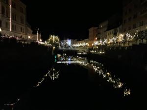 Una ciudad de noche con luces en el agua en Hostel Piero, en Liubliana