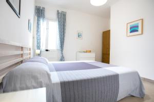 a bedroom with a bed with a blue and white blanket at Sunset Holiday House in Torre Lapillo