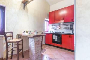 una cocina con armarios rojos y una mesa con sillas. en Biroli164 House, en Ciampino