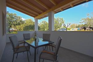 um pátio com uma mesa de vidro e cadeiras num alpendre em Apartman Topolino em Vodnjan