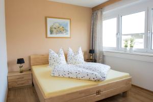 ein Schlafzimmer mit einem Bett mit weißen Kissen und einem Fenster in der Unterkunft Ferienwohnung Zillertal Bacher in Schlitters