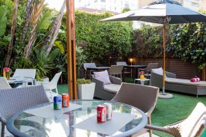 a patio with tables and chairs and an umbrella at The One 8 Hotel in Green Point - Solar Power in Cape Town