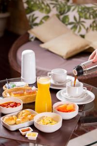 a table with a tray of breakfast foods and orange juice at Status Motel in Natal