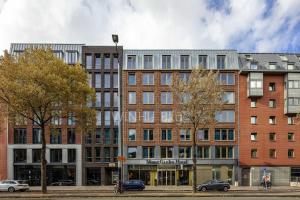 un gran edificio en una calle con árboles y coches en Monet Garden Hotel Amsterdam en Ámsterdam