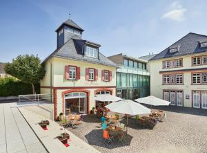 un edificio con mesas y sombrillas en un patio en Das Spritzenhaus, en Eltville am Rhein