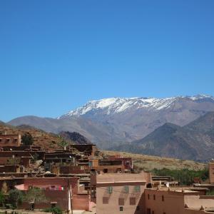 a city with snow covered mountains in the background at Ijoukak Berber HomeStay in Ijjoukak