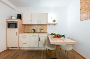 a kitchen with a wooden table and white cabinets at Apartment 1, Rothenburger Straße in Dresden