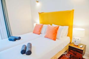 een slaapkamer met 2 bedden met oranje en blauwe kussens bij Beautiful Dreamers - at Avenida CR3D in Lissabon