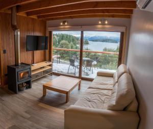 uma sala de estar com um sofá, uma televisão e uma mesa em BOG Atardeceres del lago - piscina climatizada y vistas al lago em Villa La Angostura