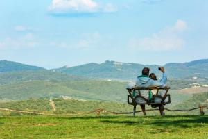 um casal sentado num banco a olhar para as montanhas em Villa Di Capovento em Castellina in Chianti