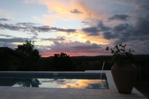 a vase sitting next to a swimming pool with a sunset at Cabañas A la Maison in Mina Clavero
