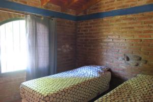 1 dormitorio con 2 camas y pared de ladrillo en Cabañas A la Maison en Mina Clavero