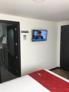 uma televisão na parede de um quarto com uma cama em Hotel Florida ApartaSuites. em Ipiales