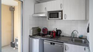 a small kitchen with a sink and a microwave at Le Marengo: Charmant, Rénové, Terrasse, Parking privé in Toulouse