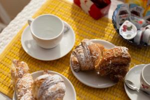 a table with plates of pastries and a cup of coffee at AlbaChiara Suite Rooms - City Center in Trapani
