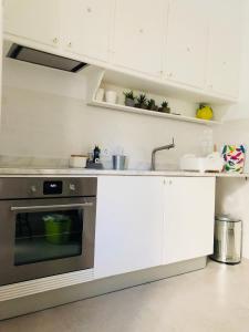 uma cozinha com armários brancos e um forno de aço inoxidável em Moderno apartamento, central e confortável em Montijo