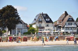 des personnes marchant sur la plage en face des maisons dans l'établissement Strandperle Lieblingsplatz Hotel, à Travemünde