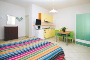 a bedroom with a bed and a table and a kitchen at Residence Stella Polare in Bibione