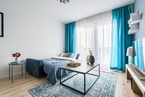 ワルシャワにあるP&O Serviced Apartments WORONICZAのリビングルーム(青いソファ、テーブル付)