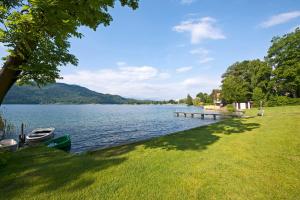 a lake with a dock and a boat on the water at Apartements Kaschitz in Pörtschach am Wörthersee