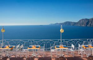 a group of tables and chairs on a balcony overlooking the water at Tramonto d'Oro in Praiano