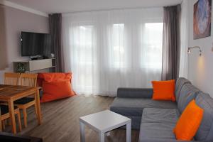 ein Wohnzimmer mit einem grauen Sofa und orangefarbenen Kissen in der Unterkunft Ski apartman Klinovec in Loučná pod Klínovcem