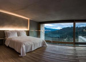 a bedroom with a bed and a large window at Escapade Luxury Residences in Karpenisi