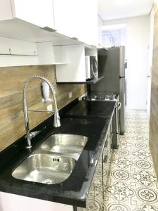 a kitchen with a sink and a black counter top at Apartamento 2 quartos, padrão hotel na Avenida Paulista in São Paulo