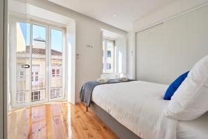 een witte slaapkamer met een bed en een groot raam bij Casa Eclea Lisbon Belem Design Apartment in Lissabon
